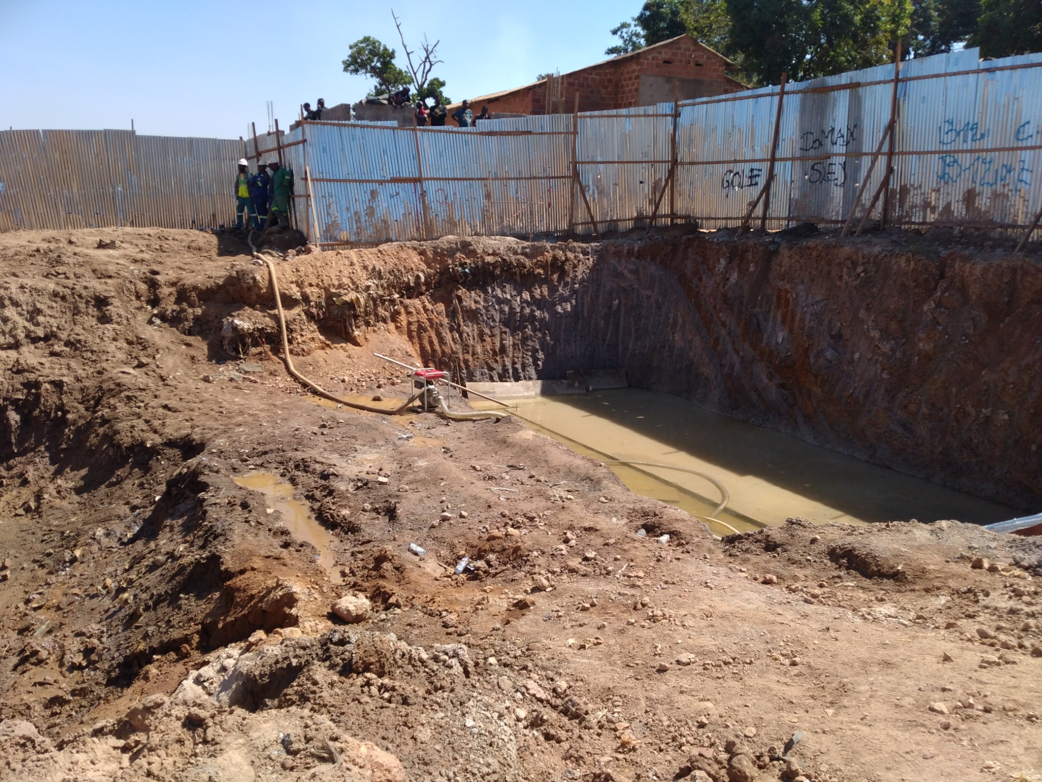 Pont FATSHI BETON — Motopompe et conduites disposées au bord d’une fouille