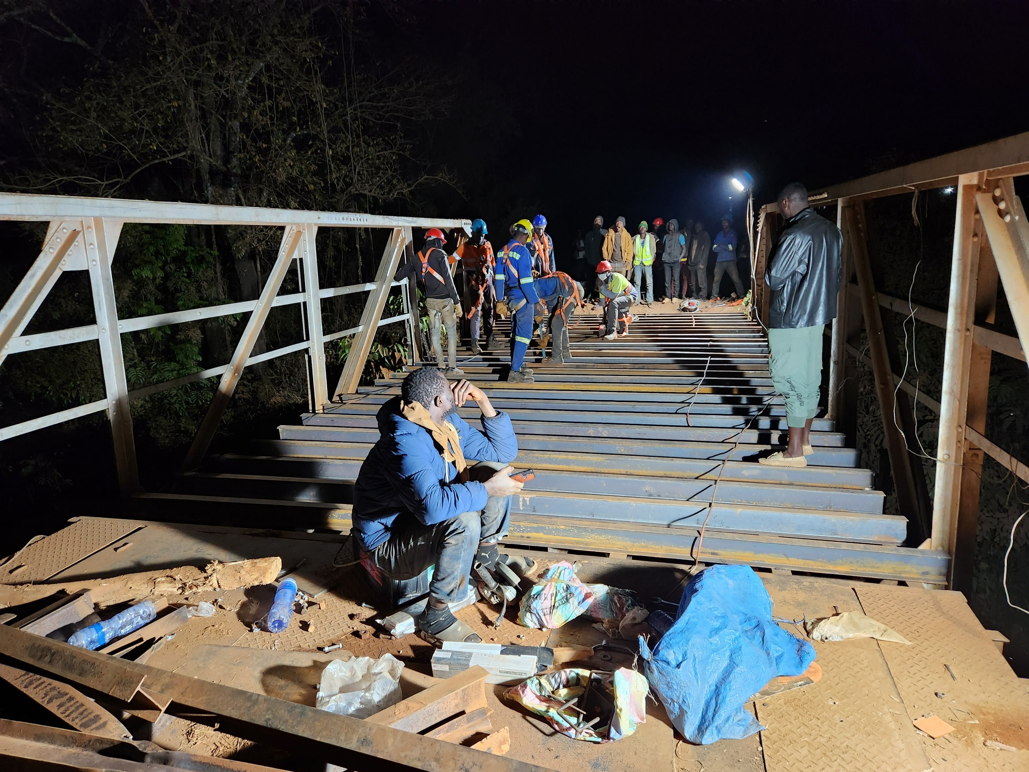 Vue de l’équipe et des traverses métalliques sous éclairage de chantier